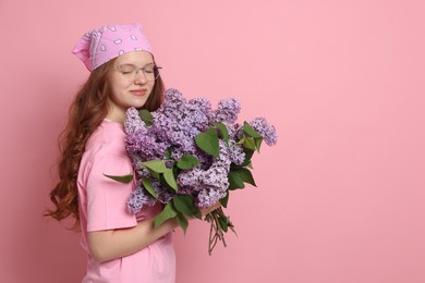 Photo of Beautiful teenage girl with bouquet of lilac flowers on pink background. Space for text
