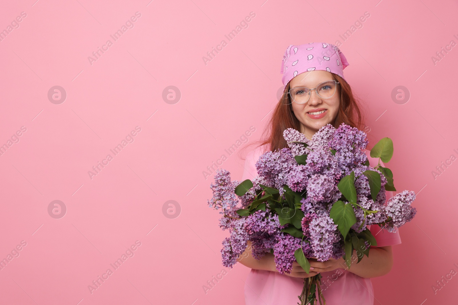 Smiling teenage girl with bouquet of lilac flowers on pink background. Space for text Photo of Smiling teenage girl with bouquet of lilac flowers on pink background. Space for text