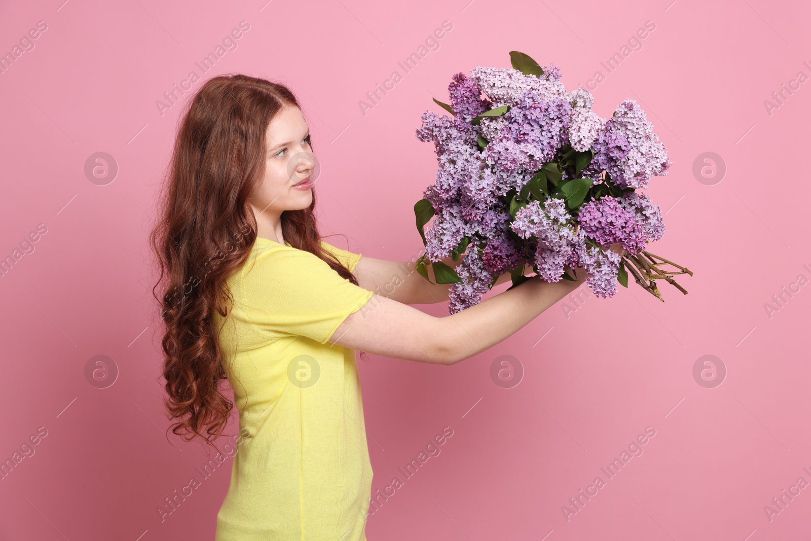 Teenage girl with bouquet of lilac flowers on pink background Photo of Teenage girl with bouquet of lilac flowers on pink background