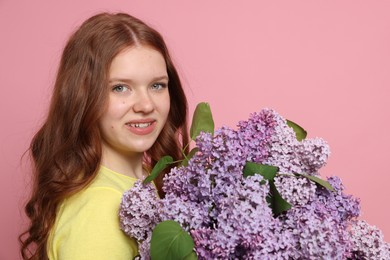 Photo of Portrait of smiling teenage girl with lilac flowers on pink background
