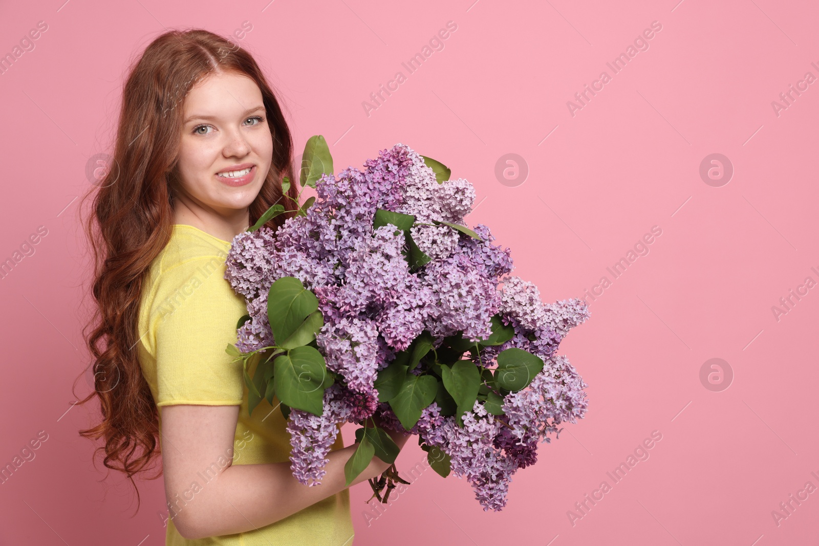 Smiling teenage girl with bouquet of lilac flowers on pink background. Space for text Photo of Smiling teenage girl with bouquet of lilac flowers on pink background. Space for text