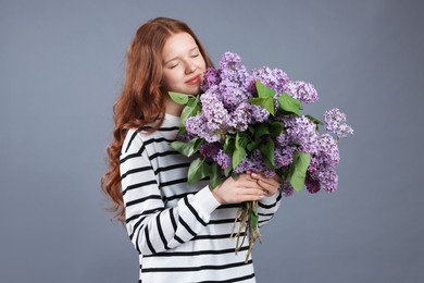 Photo of Portrait of beautiful teenage girl with lilac flowers on grey background
