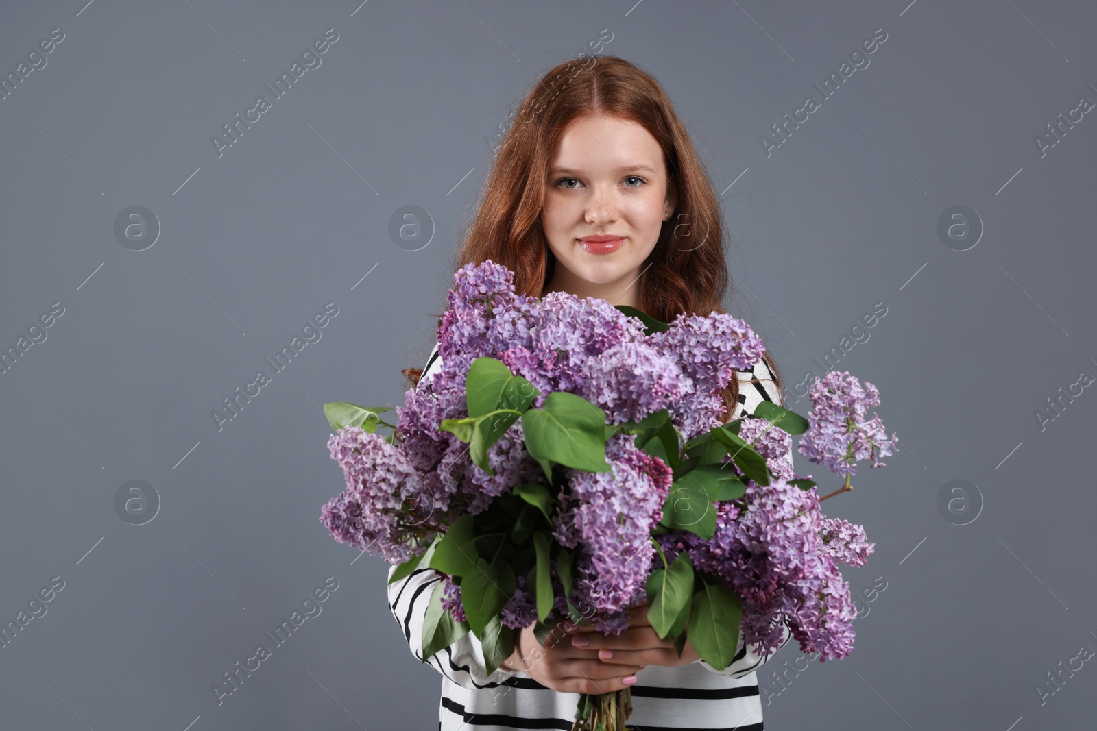 Portrait of beautiful teenage girl with lilac flowers on grey background Photo of Portrait of beautiful teenage girl with lilac flowers on grey background