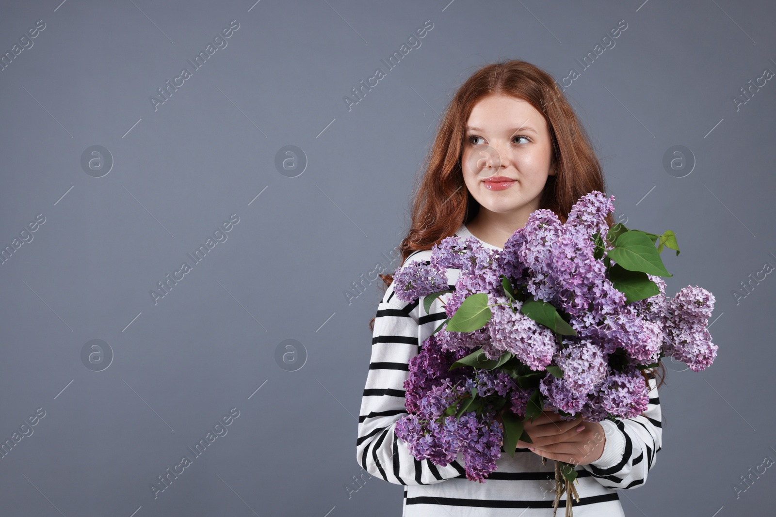 Beautiful teenage girl with bouquet of lilac flowers on grey background. Space for text Photo of Beautiful teenage girl with bouquet of lilac flowers on grey background. Space for text