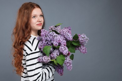 Photo of Beautiful teenage girl with bouquet of lilac flowers on grey background. Space for text