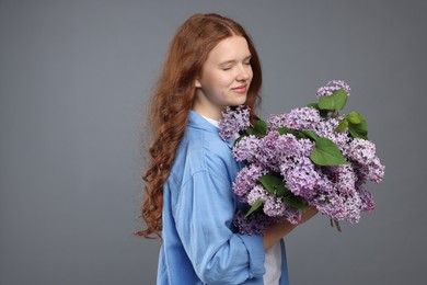 Photo of Portrait of beautiful teenage girl with lilac flowers on grey background