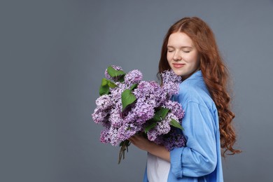 Photo of Beautiful teenage girl with bouquet of lilac flowers on grey background. Space for text