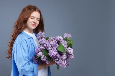 Photo of Beautiful teenage girl with bouquet of lilac flowers on grey background. Space for text
