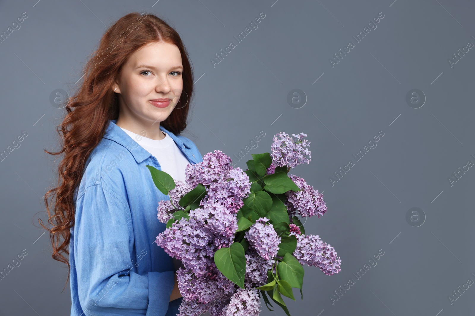 Beautiful teenage girl with bouquet of lilac flowers on grey background. Space for text Photo of Beautiful teenage girl with bouquet of lilac flowers on grey background. Space for text