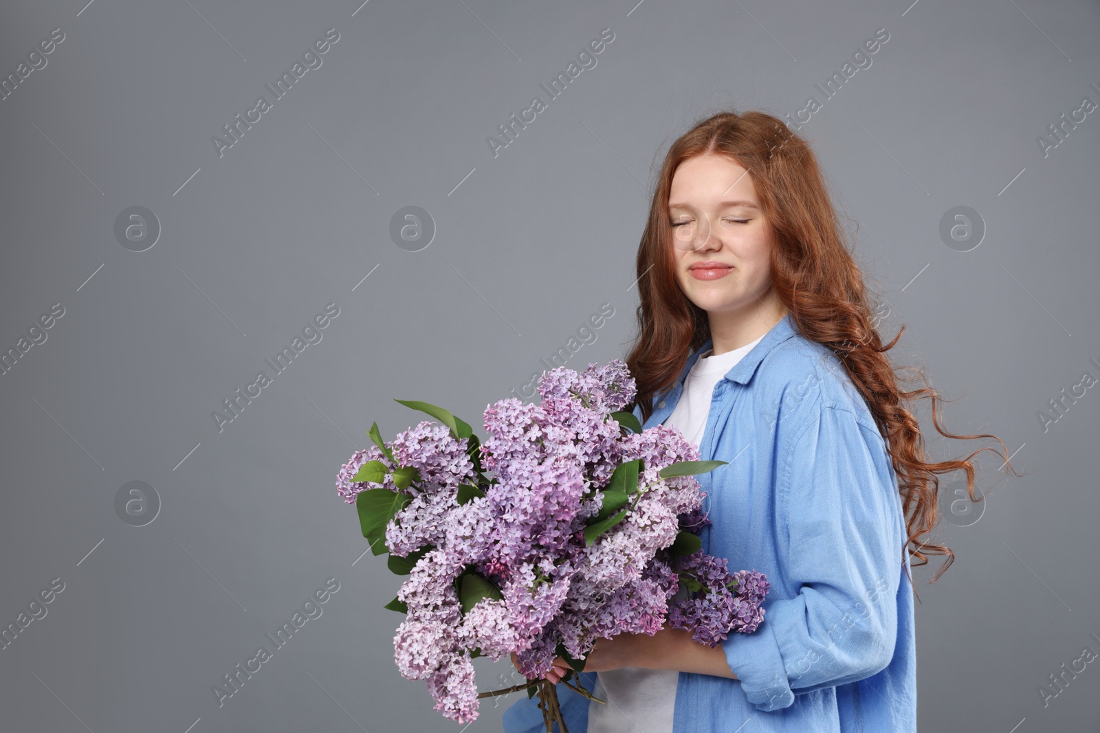 Beautiful teenage girl with bouquet of lilac flowers on grey background. Space for text Photo of Beautiful teenage girl with bouquet of lilac flowers on grey background. Space for text