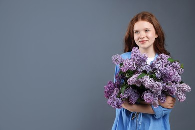 Photo of Beautiful teenage girl with bouquet of lilac flowers on grey background. Space for text