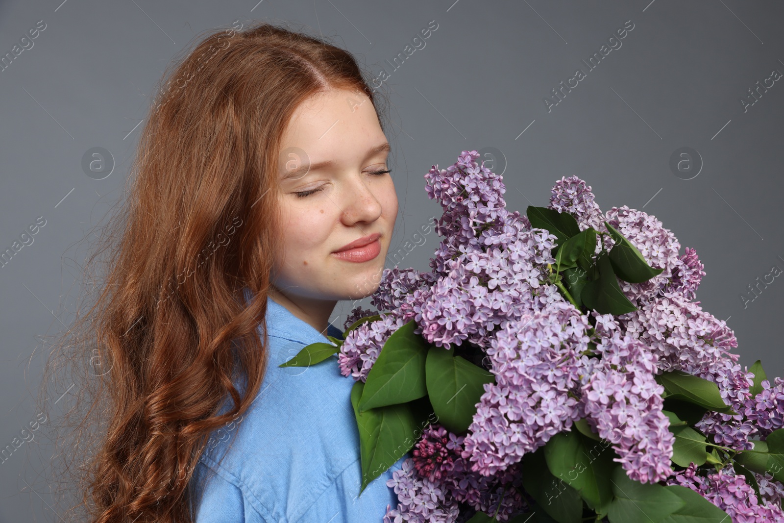 Portrait of beautiful teenage girl with lilac flowers on grey background Photo of Portrait of beautiful teenage girl with lilac flowers on grey background