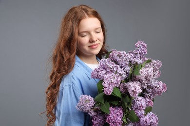 Photo of Portrait of beautiful teenage girl with lilac flowers on grey background