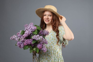 Photo of Portrait of smiling teenage girl with lilac flowers on grey background