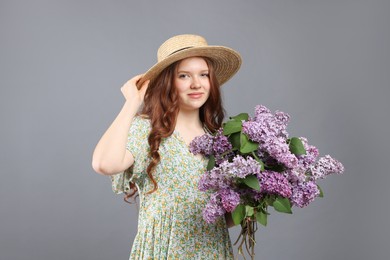 Photo of Portrait of beautiful teenage girl with lilac flowers on grey background