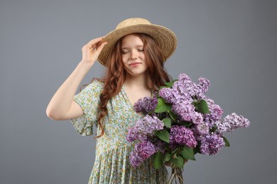 Photo of Portrait of beautiful teenage girl with lilac flowers on grey background