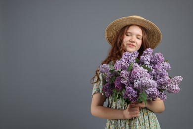 Photo of Beautiful teenage girl with bouquet of lilac flowers on grey background. Space for text