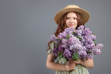 Photo of Beautiful teenage girl with bouquet of lilac flowers on grey background. Space for text