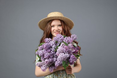 Photo of Portrait of smiling teenage girl with lilac flowers on grey background
