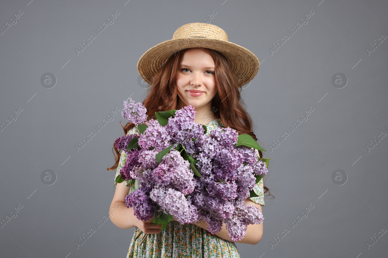 Portrait of beautiful teenage girl with lilac flowers on grey background Photo of Portrait of beautiful teenage girl with lilac flowers on grey background