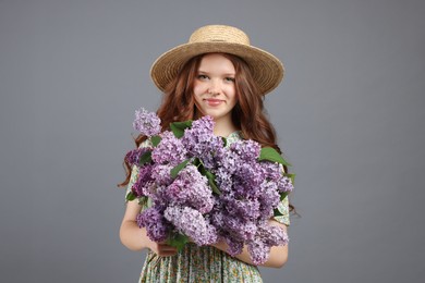 Photo of Portrait of beautiful teenage girl with lilac flowers on grey background