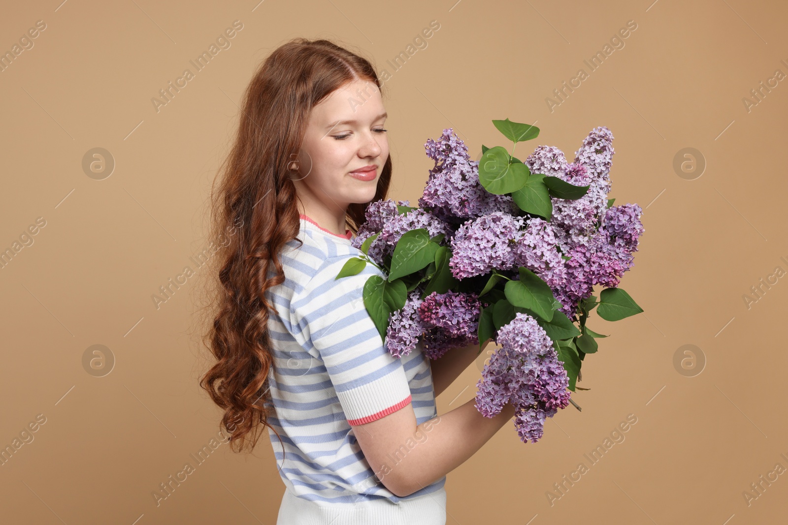 Beautiful teenage girl with bouquet of lilac flowers on beige background Photo of Beautiful teenage girl with bouquet of lilac flowers on beige background