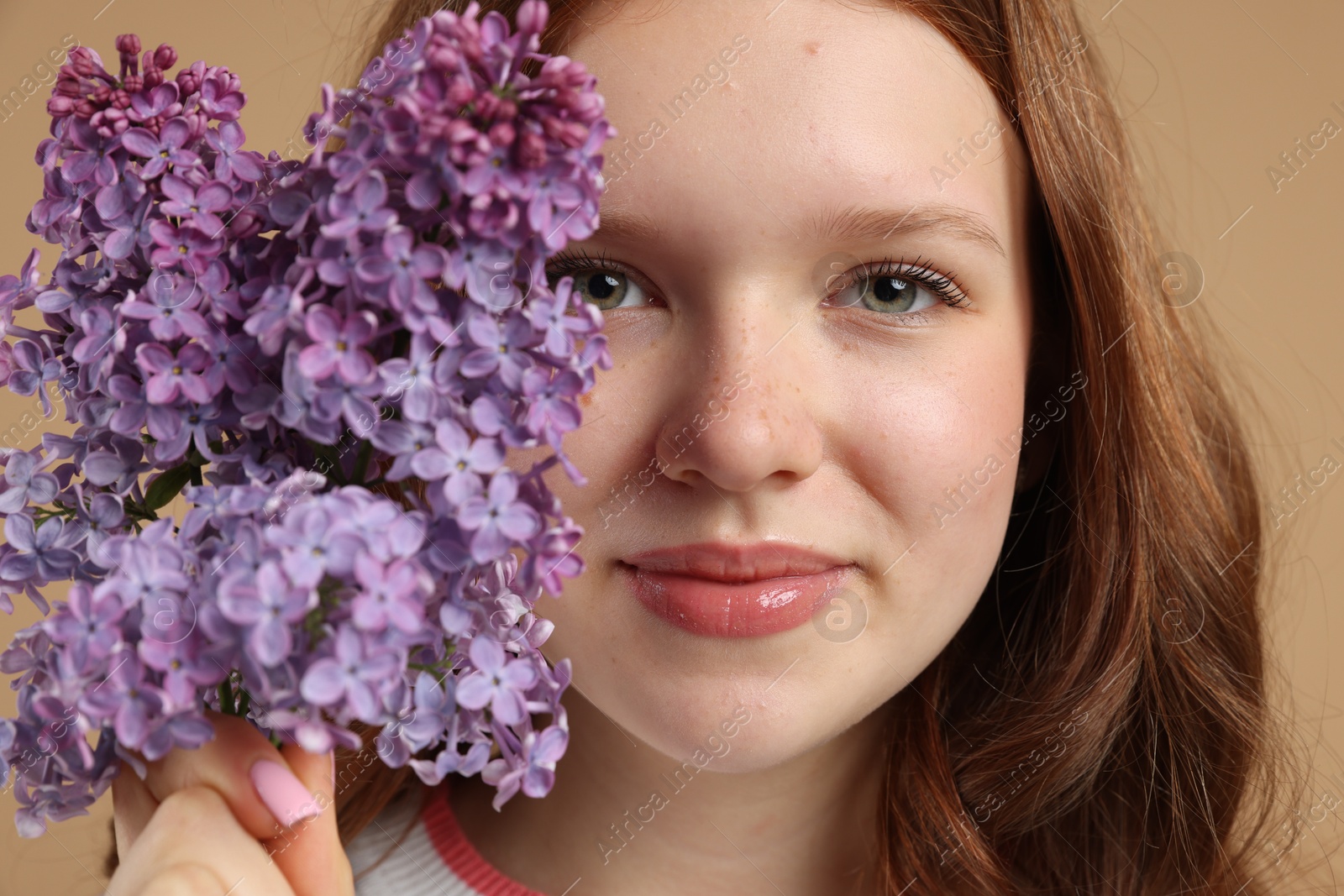 Beautiful teenage girl with lilac flowers on beige background, closeup Photo of Beautiful teenage girl with lilac flowers on beige background, closeup