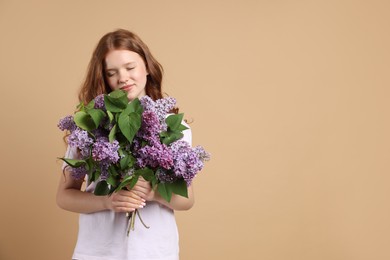 Photo of Beautiful teenage girl with bouquet of lilac flowers on beige background. Space for text