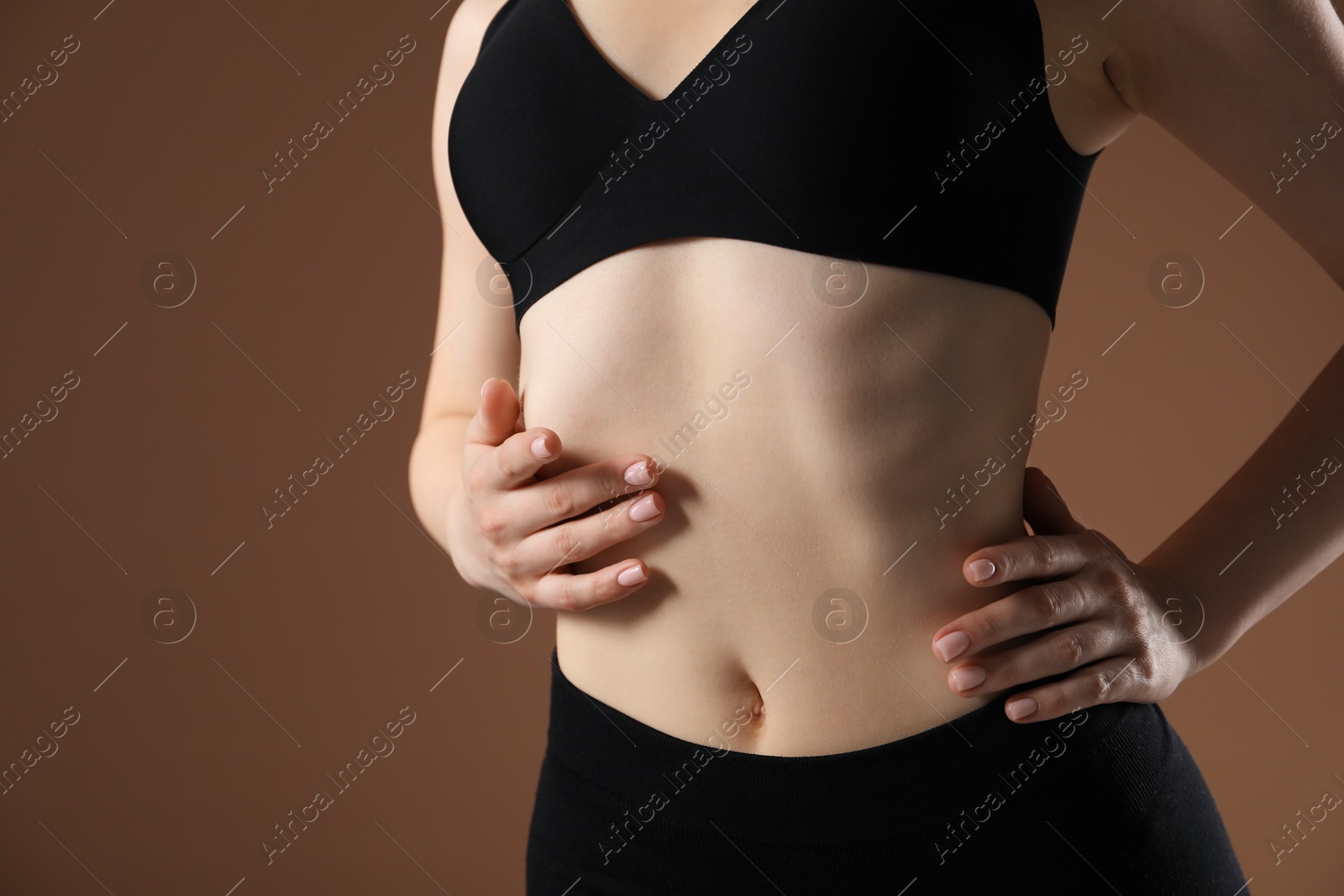 Attractive woman against brown background, closeup on belly Photo of Attractive woman against brown background, closeup on belly