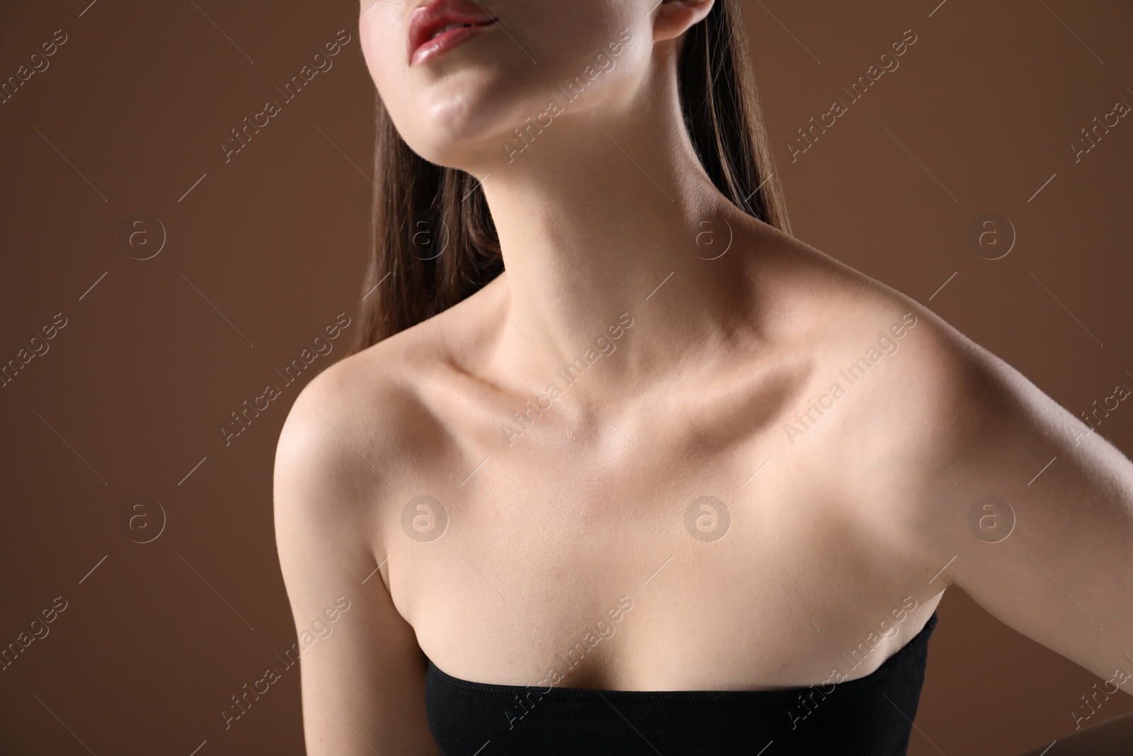 Woman with beautiful collarbones on brown background, closeup Photo of Woman with beautiful collarbones on brown background, closeup