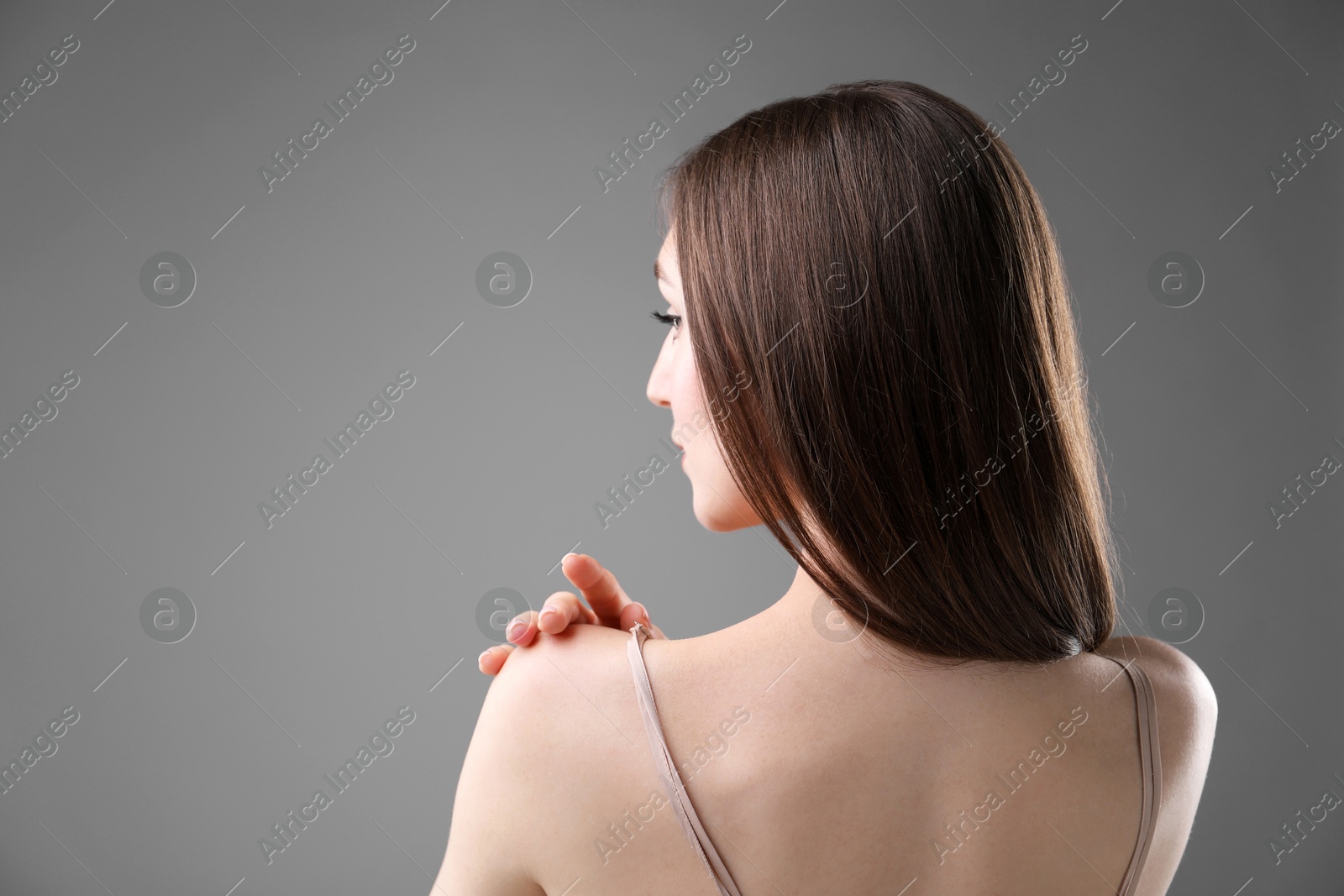 Beautiful woman on grey background, back view. Space for text Photo of Beautiful woman on grey background, back view. Space for text