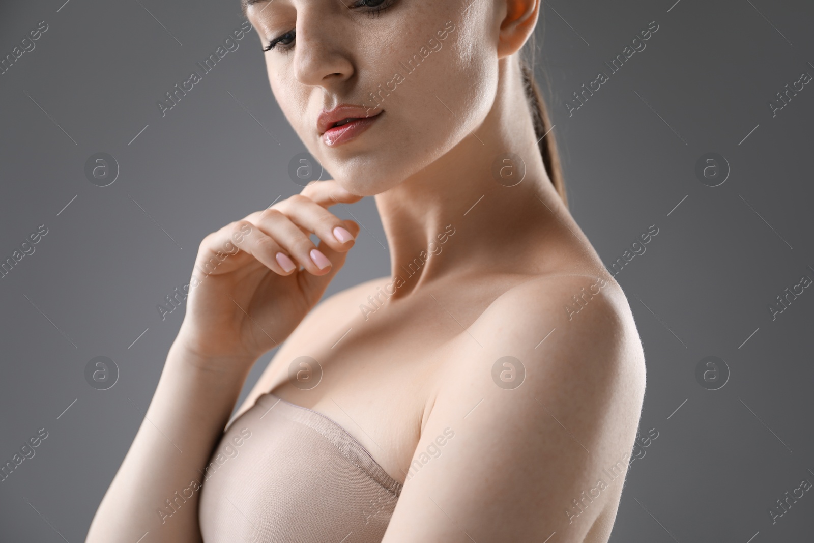 Attractive woman against grey background, closeup on shoulder Photo of Attractive woman against grey background, closeup on shoulder
