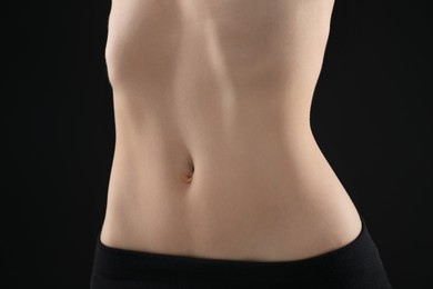 Photo of Attractive woman against black background, closeup on belly
