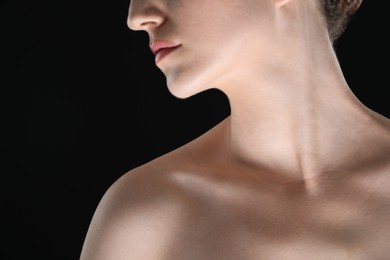 Photo of Woman with beautiful collarbones and neck on black background, closeup