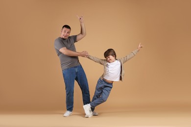 Photo of Father and his son dancing together on beige background