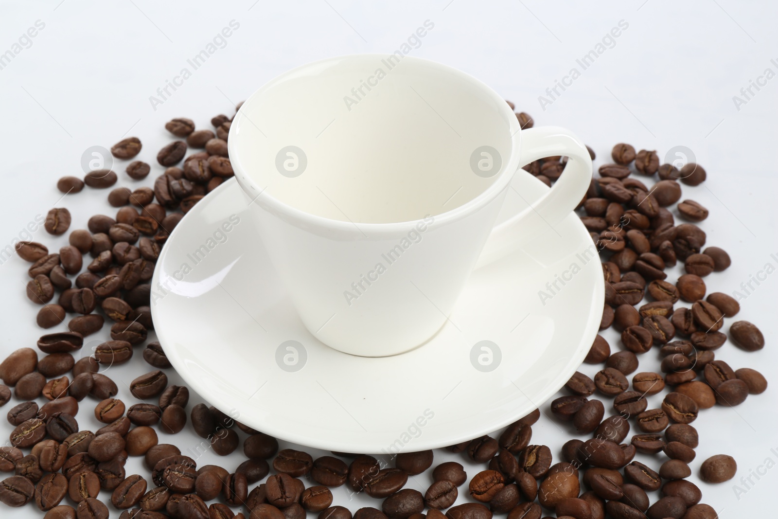 Ceramic cup with roasted coffee beans isolated on white Photo of Ceramic cup with roasted coffee beans isolated on white