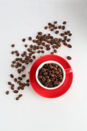 Photo of Ceramic cup with roasted coffee beans on white background, top view