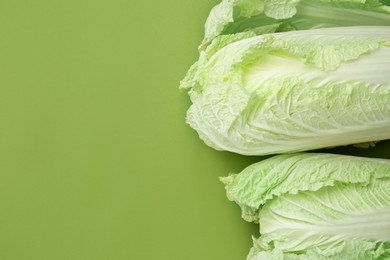 Photo of Fresh Chinese cabbages on green background, top view. Space for text