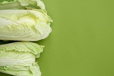 Photo of Fresh Chinese cabbages on green background, top view. Space for text