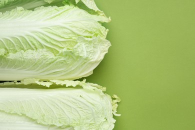Photo of Fresh Chinese cabbages on green background, top view. Space for text