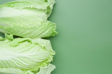 Photo of Fresh Chinese cabbages on green background, top view. Space for text