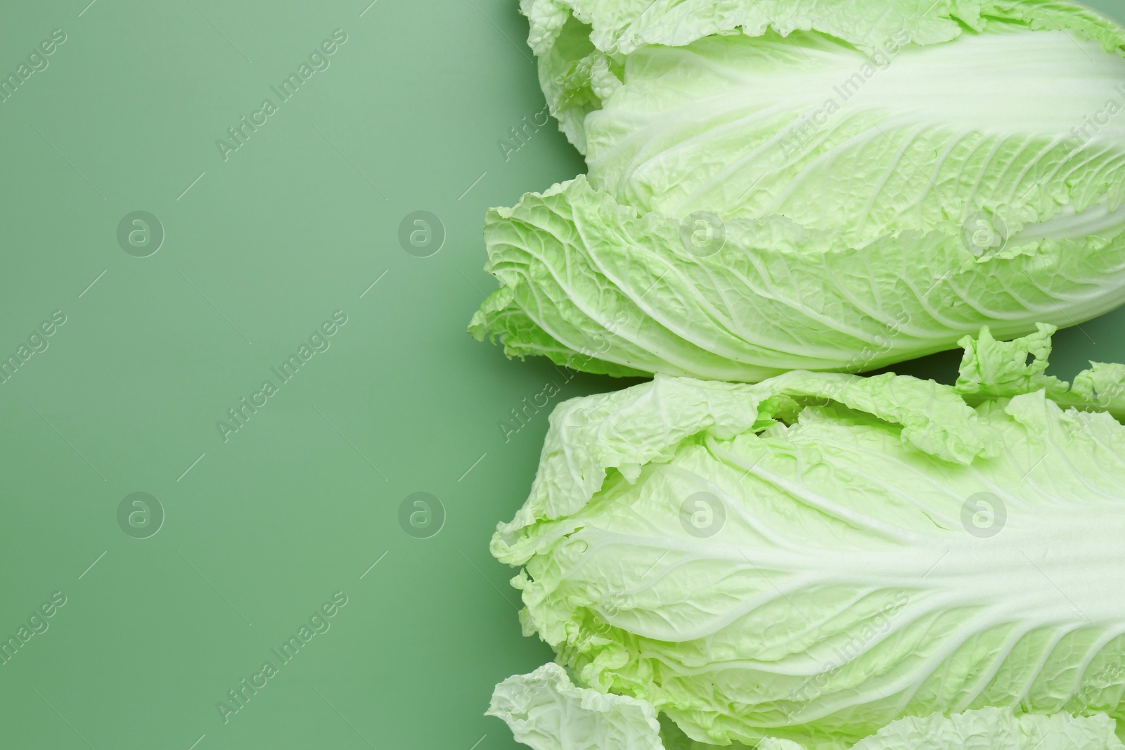 Fresh Chinese cabbages on green background, top view. Space for text Photo of Fresh Chinese cabbages on green background, top view. Space for text