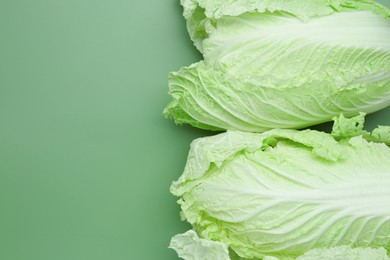 Photo of Fresh Chinese cabbages on green background, top view. Space for text