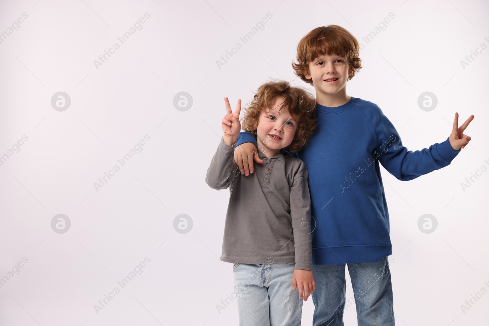 Cute little brothers showing V-signs on white background. Space for text Photo of Cute little brothers showing V-signs on white background. Space for text