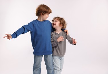 Photo of Cute little brothers showing V-signs on white background