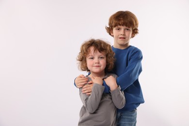 Photo of Cute little brothers hugging on white background. Space for text