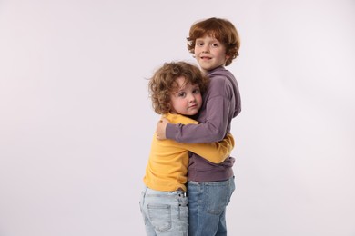 Photo of Cute little brothers hugging on white background. Space for text