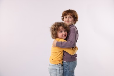 Photo of Cute little brothers hugging on white background. Space for text