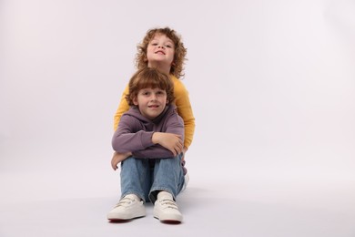 Photo of Cute little brothers posing on white background