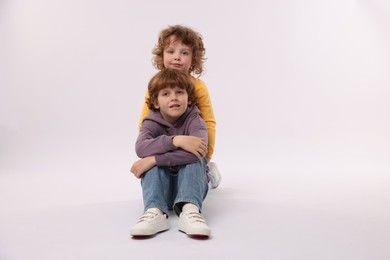 Photo of Cute little brothers posing on white background